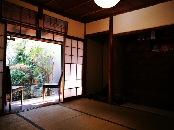 Ein traditioneller japanischer Raum mit Tatami-Boden, Schiebetüren und Blick auf Grünfläche.