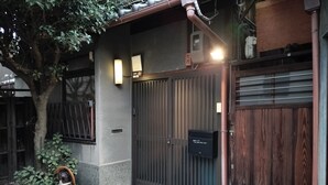 Una entrada porticada con un buzón, un árbol pequeño y una estatua decorativa.