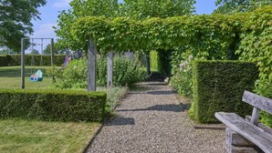 Un sendero de grava que atraviesa un jardín con un banco de madera a la derecha.
