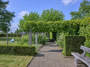 A gravel pathway leading through a garden with a wooden bench on the right.