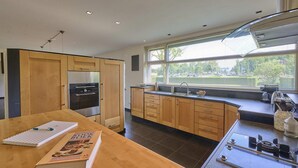 Una cocina moderna con armarios de madera, horno empotrado y un amplio ventanal con vistas al exterior.