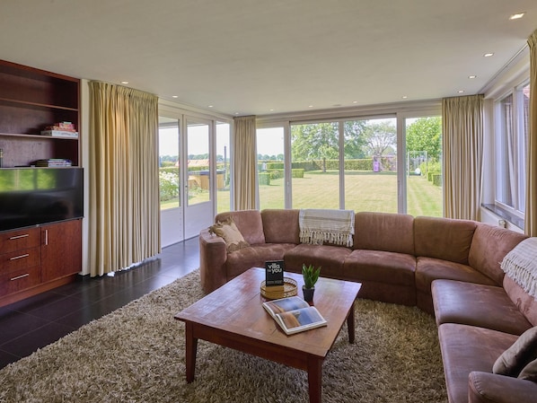 A spacious living room with a large sectional sofa, a wooden coffee table, and a bookshelf.