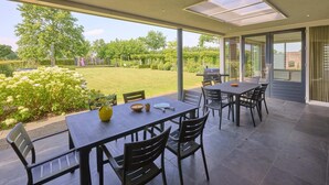 Un patio con mesa y sillas, una parrilla y vistas de un jardín.