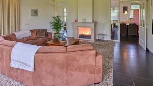 Una sala de estar con sofá, chimenea, comedor y cocina a la vista a través de una puerta abierta.