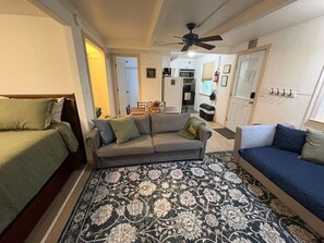 A compact living space with a sofa, two beds, a patterned rug, a ceiling fan, and a kitchen area in the background. - Yosemite West Retreat -Inside National Park - A-Frame Cabin (TUOLUMNE MEADOWS)