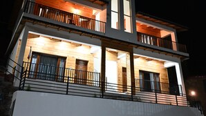 A two-story building with a balcony on the upper floor, a wooden facade, and a white base.