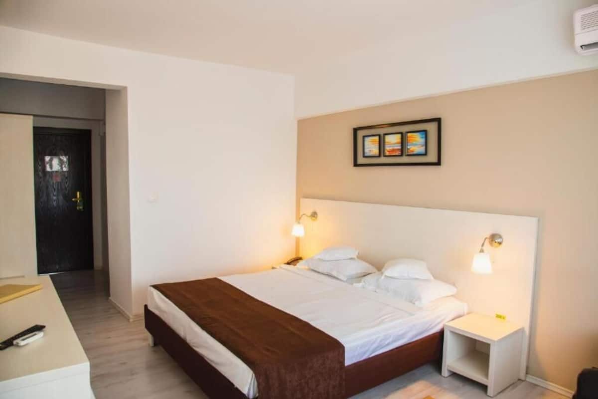 Una habitación de hotel con cama, mesitas de noche y un cuadro colgado en la pared.