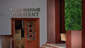 Puinen ovi, jossa on sydämenmuotoinen koriste, kyltti, jossa lukee ”Restaurant AMBIENT”, ja vihreä pystysuora puutarha.