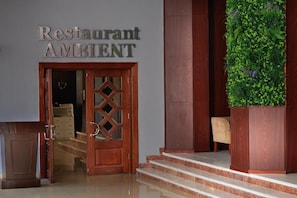 A wooden door with a heart-shaped decoration, a sign reading 'Restaurant AMBIENT,' and a green vertical garden. - Hotel Ambasador Mamaia (Constanța)