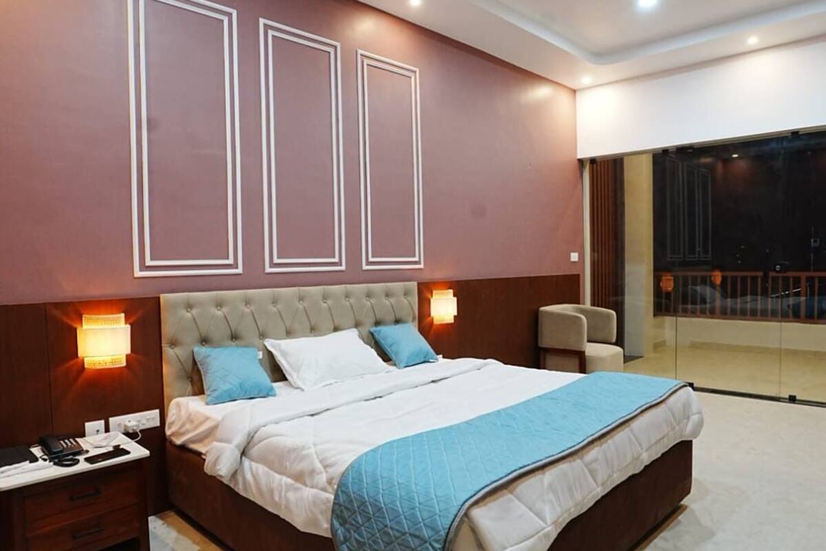 A modern bedroom with a large bed, bedside tables, a ceiling fan, and a view of the outside.