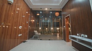 Un intérieur moderne avec un lambris en bois, des spots encastrés au plafond, un coin salon comprenant une chaise et une petite table, et une cloison en verre.