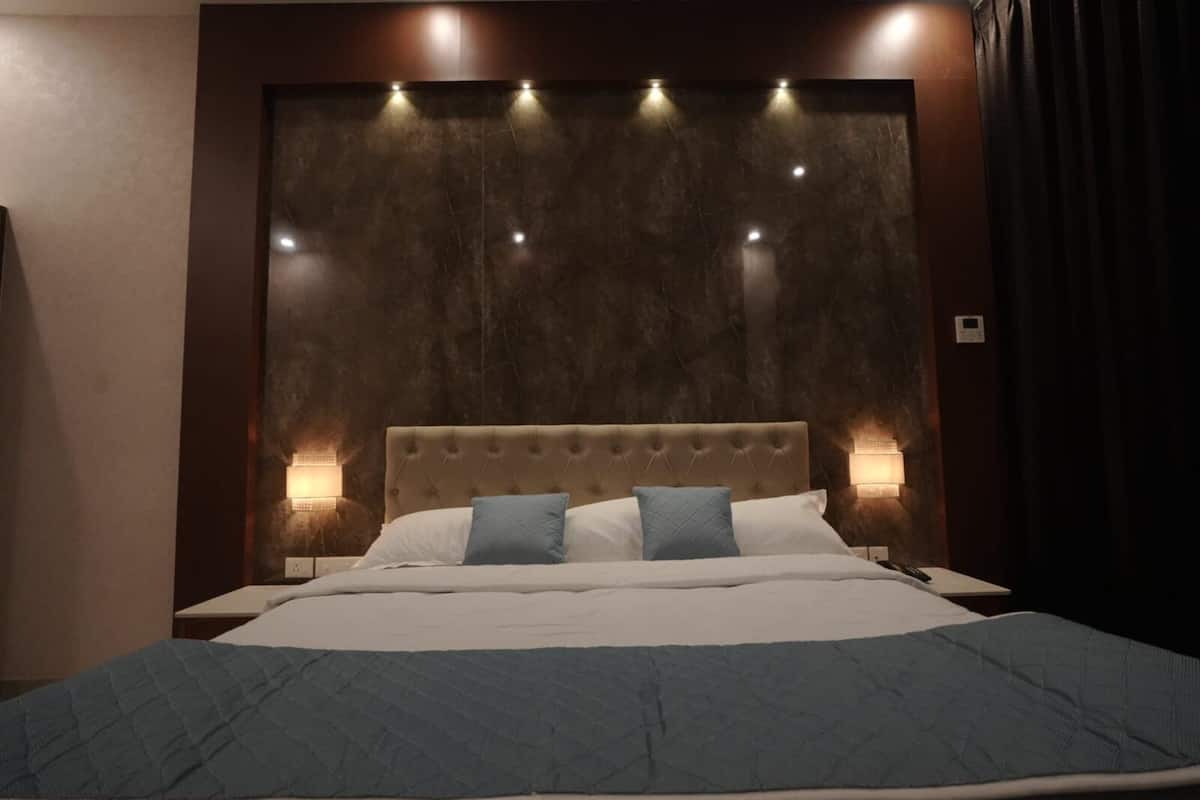 A bed with a tufted headboard, two pillows, and a blue quilt.