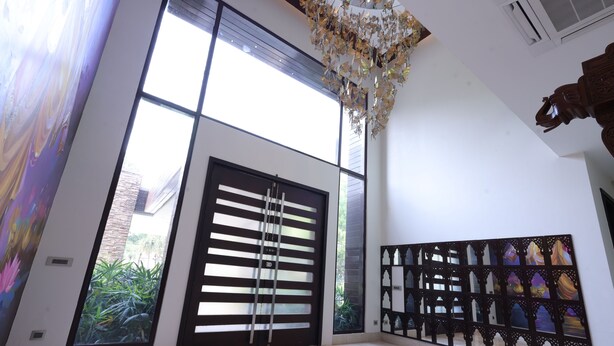 A spacious room with a large sliding door, a decorative wall panel, and a ceiling light fixture. - Stepstones Estate (New Delhi)