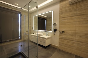 A modern bathroom with a glass shower enclosure, a white vanity with a large mirror, and a wall-mounted towel rack.