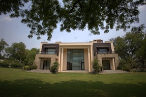 A modern two-story house with a large glass front door, a stone facade, and a well-maintained lawn.