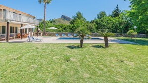 Ein Poolbereich mit Liegestühlen, einer Palme und einem Berg im Hintergrund.