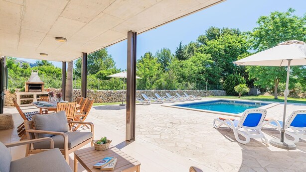 Eine Außenpatio mit Pool, Liegestühlen, einem Tisch und einem Grill.