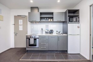 Une cuisine moderne avec des meubles gris, un four encastré, un four à micro-ondes et un réfrigérateur.