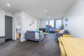 Un salon moderne avec un canapé, une table à manger et un balcon offrant une vue agréable.