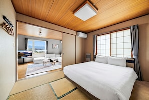 Habitación de hotel con una cama grande, un sofá, un televisor y vistas a la montaña desde la ventana.