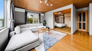 Una sala moderna con sofá, mesa de centro y vistas a un dormitorio a través de un umbral abierto.