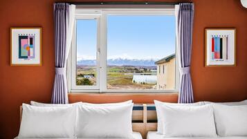 A hotel room with two beds, a window with curtains, and framed pictures on the walls.