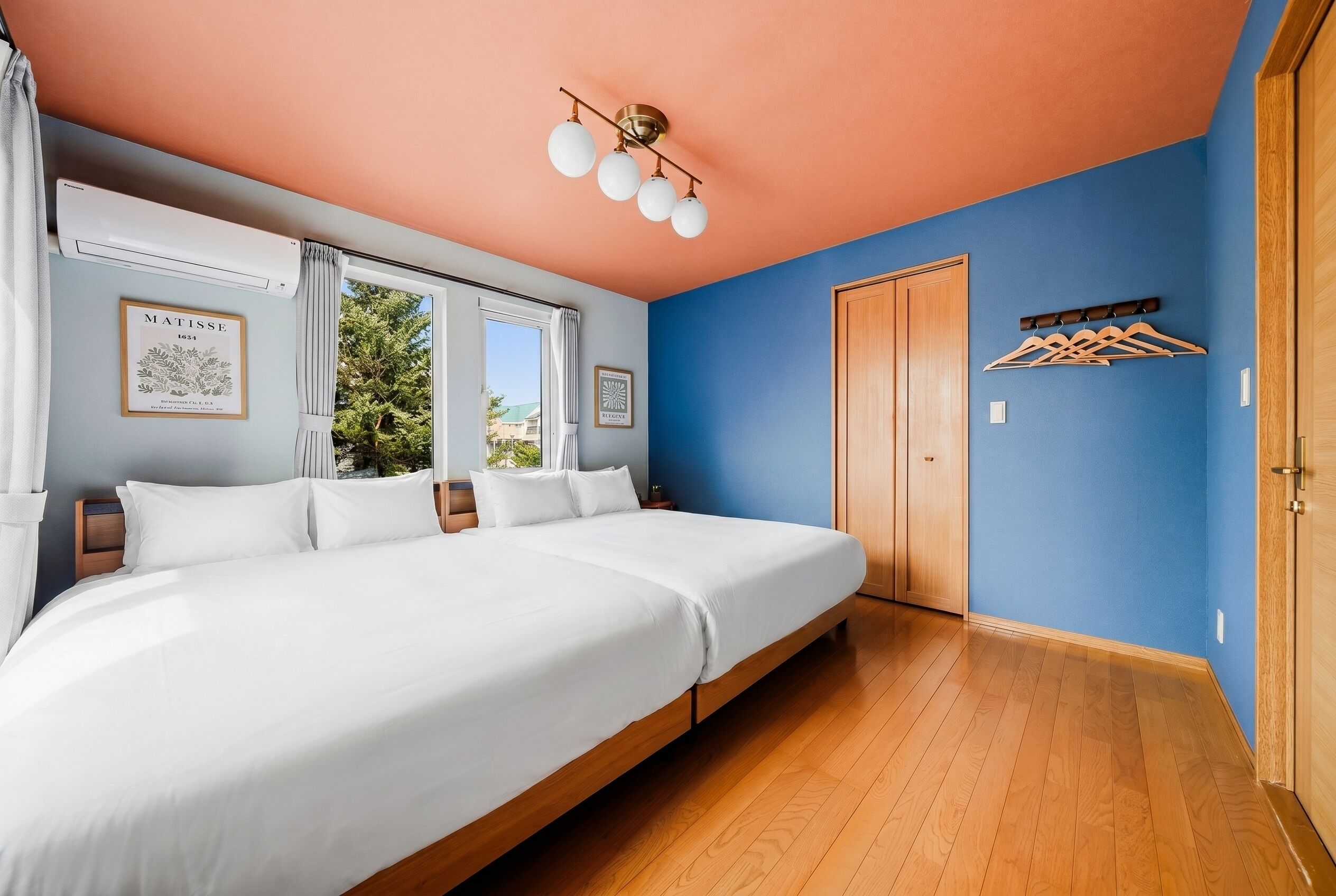 A bedroom with a large bed, a ceiling fan, a window with curtains, and a door.