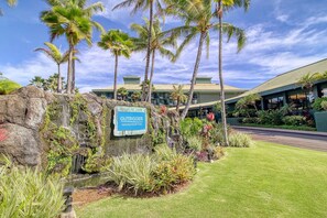 Señal del Outrigger Kauai Beach Resort & Spa, rodeada de exuberante vegetación y palmeras.