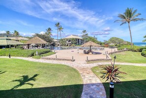 Un resort con un área de piscina central, rodeado de palmeras y una playa.