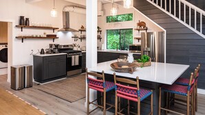 Una cocina moderna con una isla central, electrodomésticos de acero inoxidable y una zona de comedor con taburetes de bar.