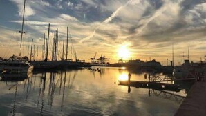 Ein Yachthafen mit vertäuten Booten, ruhigem Wasser und einem Sonnenuntergang im Hintergrund.