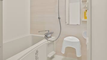 A modern bathroom with a bathtub, shower, toilet, and a mirror.