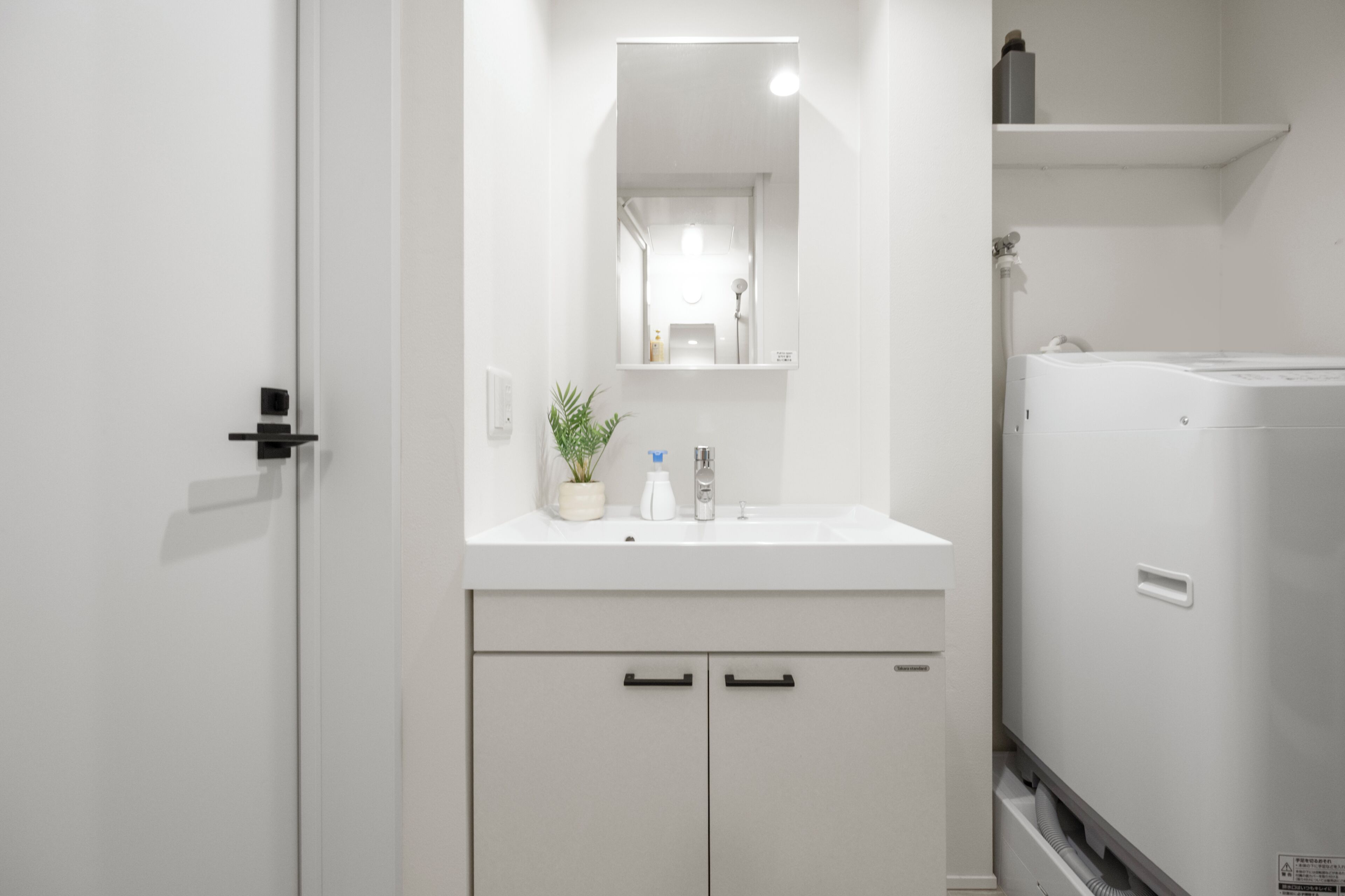A modern bathroom with a white sink, mirror, and cabinets.