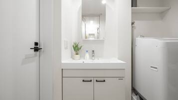 A modern bathroom with a white sink, mirror, and cabinets.