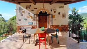 Un patio con tavolo e sedie di legno, una porta in legno e vista sulla campagna.