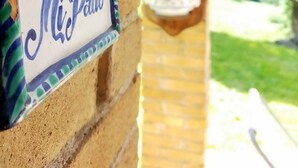 Un muro di mattoni con un cartello decorativo che riporta la scritta 'Mi Patio' e una piccola statuina.