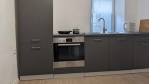 A modern kitchen with grey cabinets, a Bosch oven, a sink, and a window with a view. - 4 Persons apartment in the Eifel (Baustert)