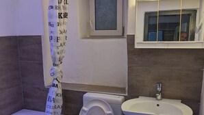 A bathroom with a toilet, a sink, a shower curtain, and a window. - 4 Persons apartment in the Eifel (Baustert)