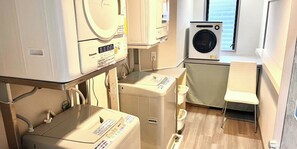 Una sala de lavandería con lavadora, secadora y unidades apiladas de lavadora-secadora.