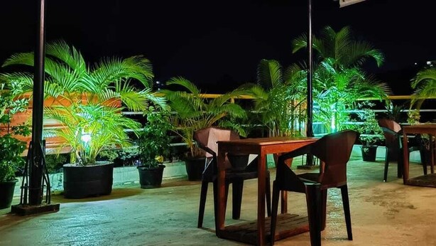 An outdoor seating area with tables and chairs, surrounded by potted plants. - Andaman Beach Resort (Port Blair)