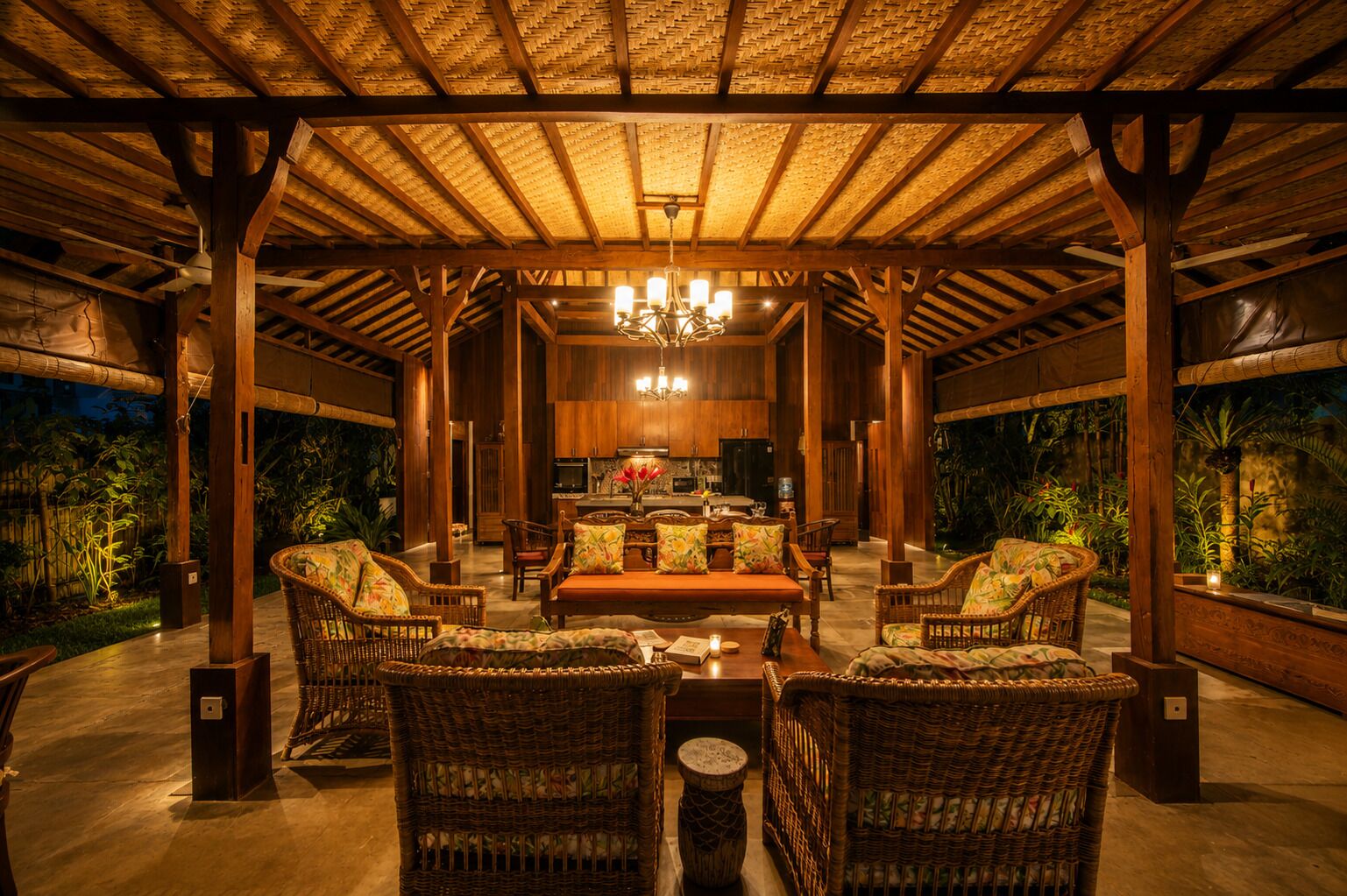 A covered outdoor seating area with wicker furniture, a central sofa, and a kitchen in the background.