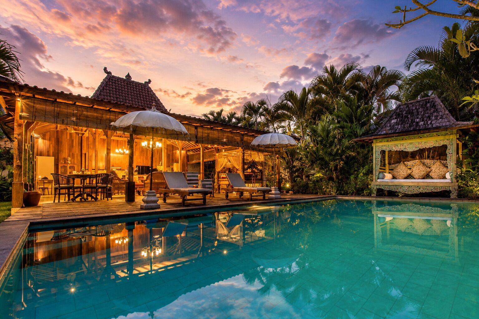 A poolside area with lounge chairs, a covered seating area, and a small pavilion with cushions.