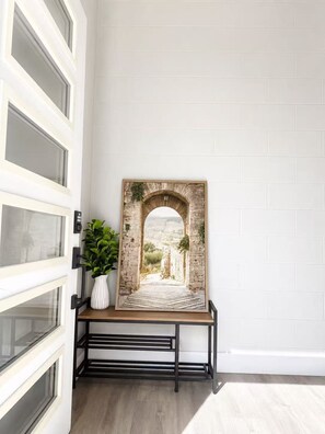 A framed picture of an archway with a view of a landscape, placed on a black metal stand against a white wall.
