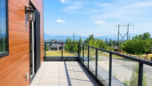 A balcony with a view of a house and mountains in the distance. - Modern 2 Bedroom Lakeview Suite (Kelowna)