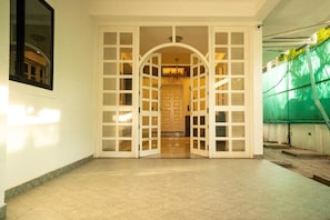 A hallway with a tiled floor and white doors with glass panels.