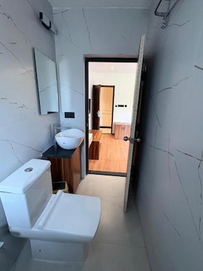 A narrow bathroom with a toilet, sink, and a mirror on the wall.