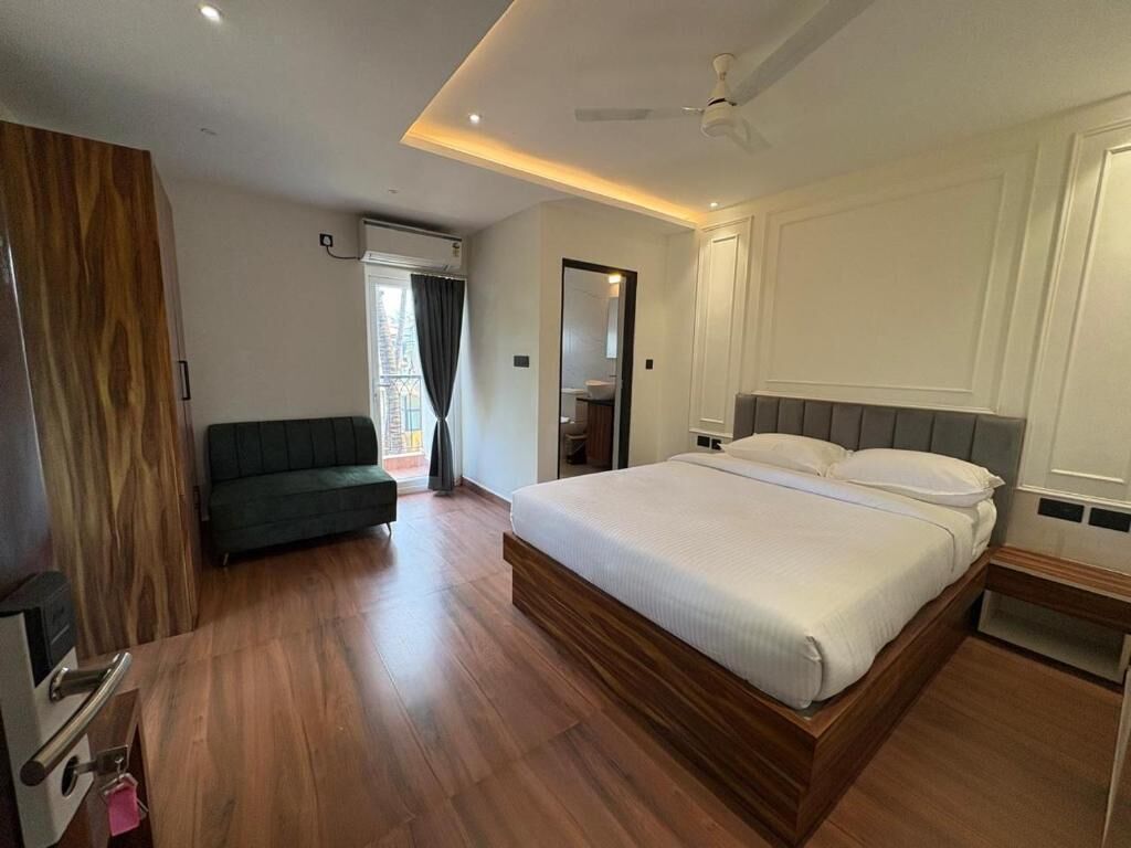 Un dormitorio con cama, sofá, ventilador de techo y puerta que da a un balcón.