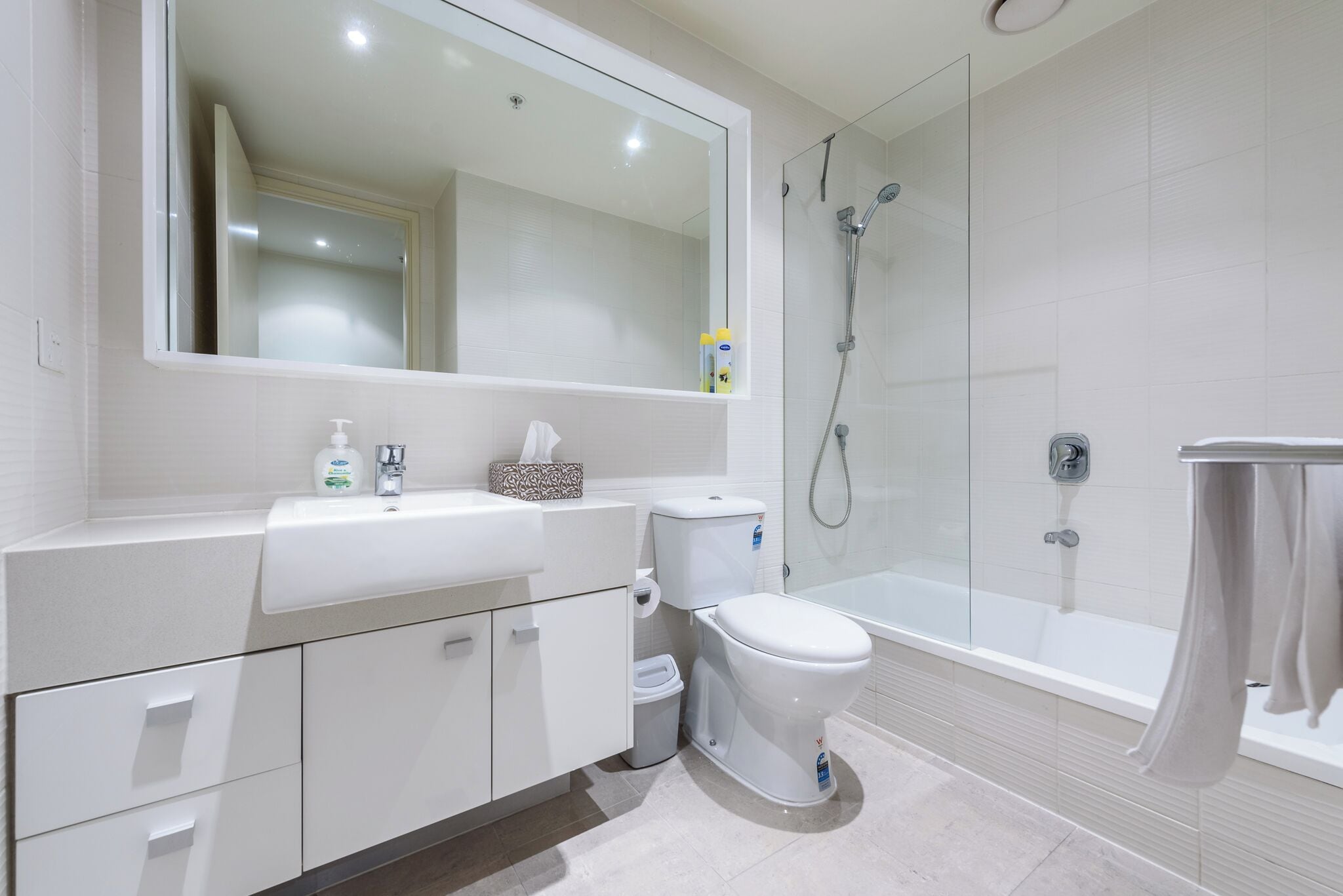 Un baño moderno con lavamanos, inodoro y bañera blancos.