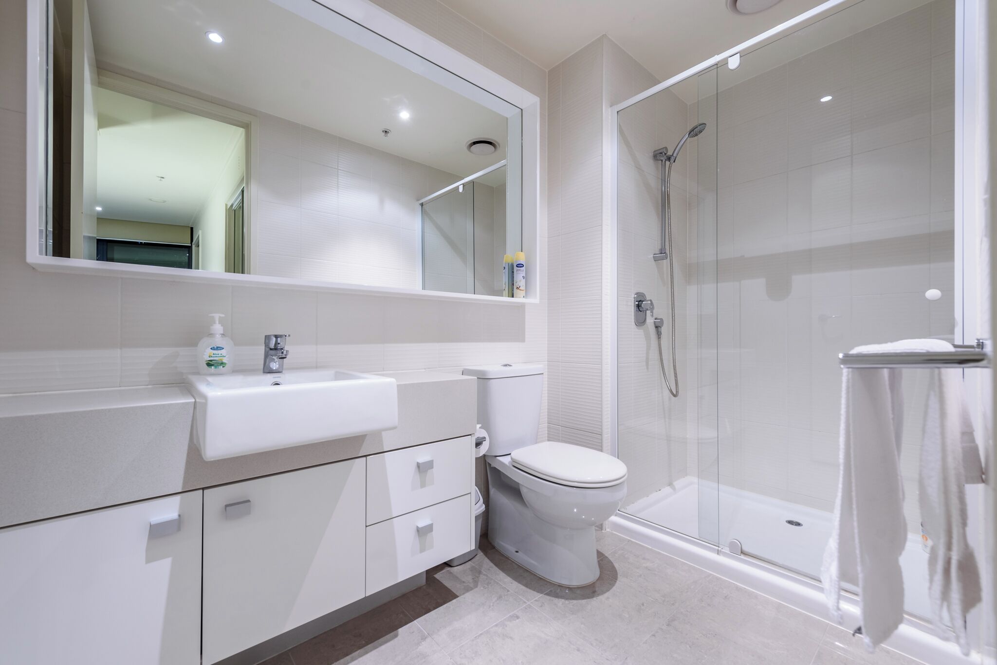 A modern bathroom with a white sink, toilet, and glass-enclosed shower.