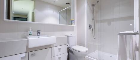 A modern bathroom with a white sink, toilet, and glass-enclosed shower.